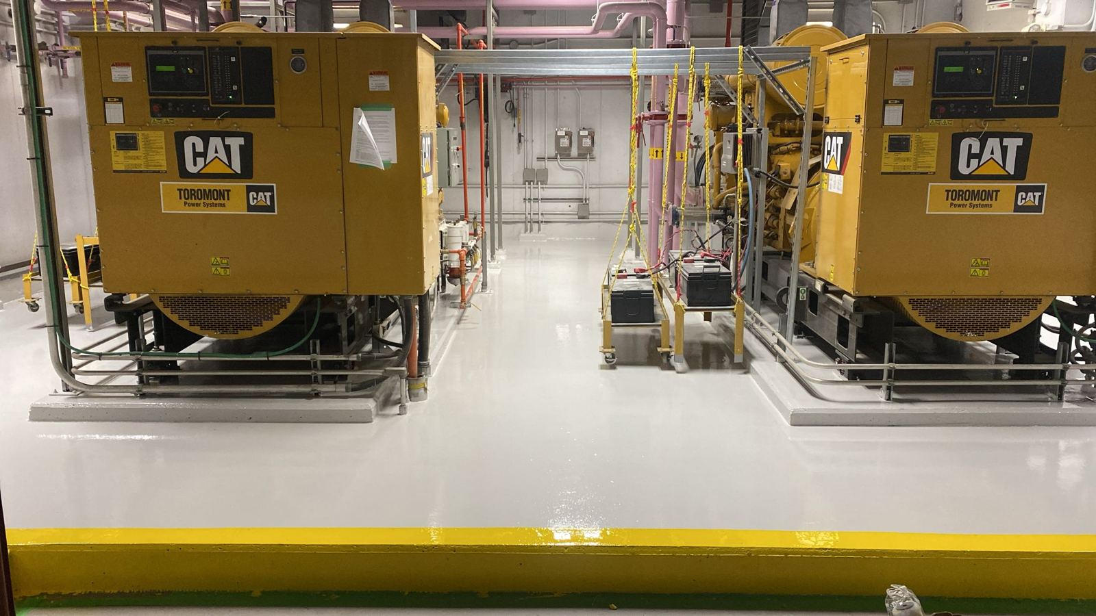 Grey epoxy floor with yellow safety curb in a generator room